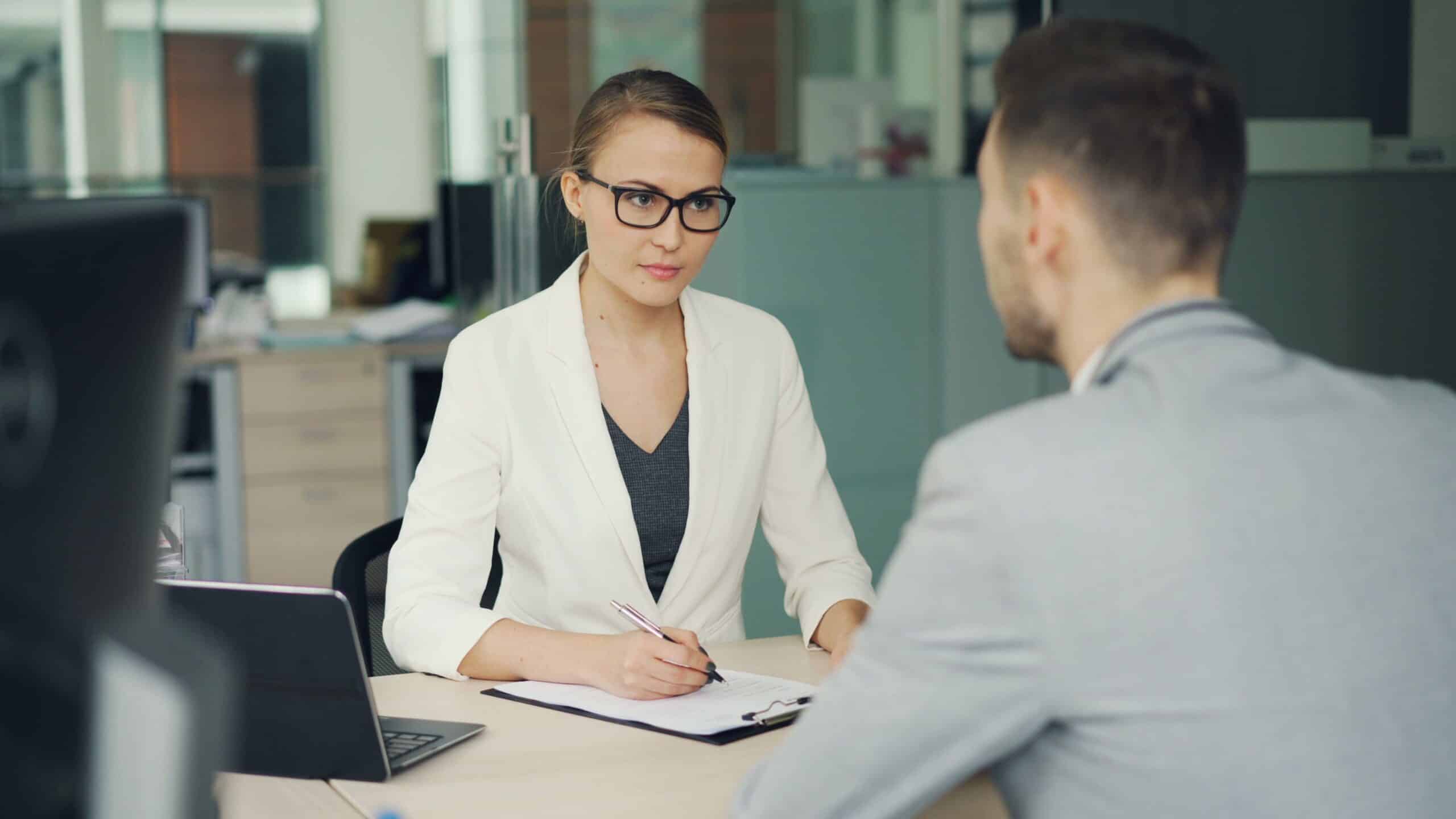 Two professionals in a serious interview discussion at an office table