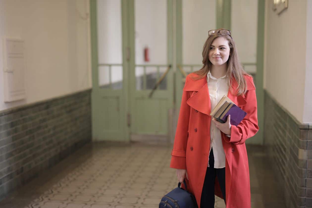 Adult student with books and backpack in a college hallway