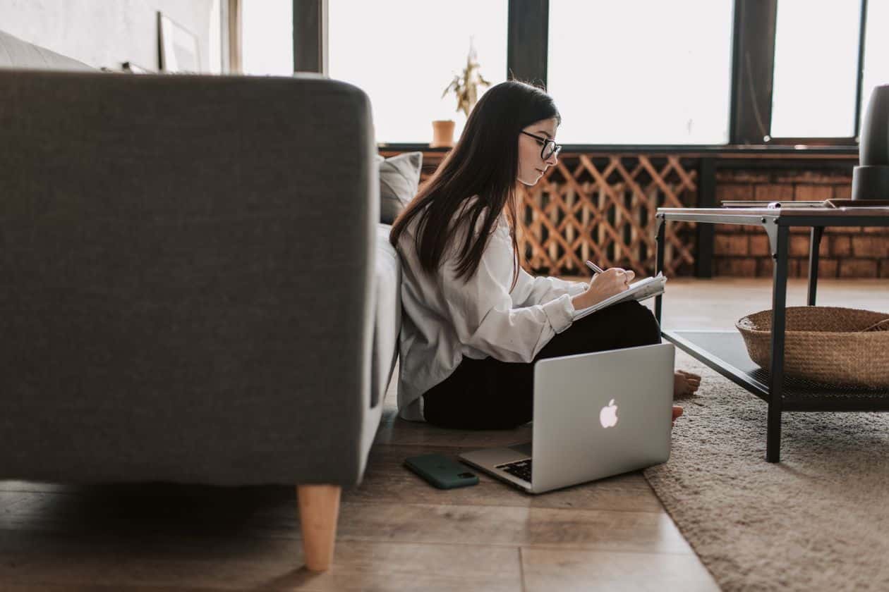 Woman writing notes beside her laptop while working through an online degree enrollment checklist