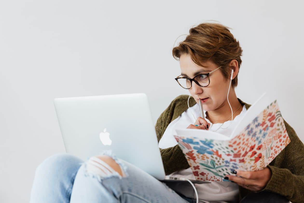 Woman concentrating while taking notes on a laptop, mapping out her financial plan