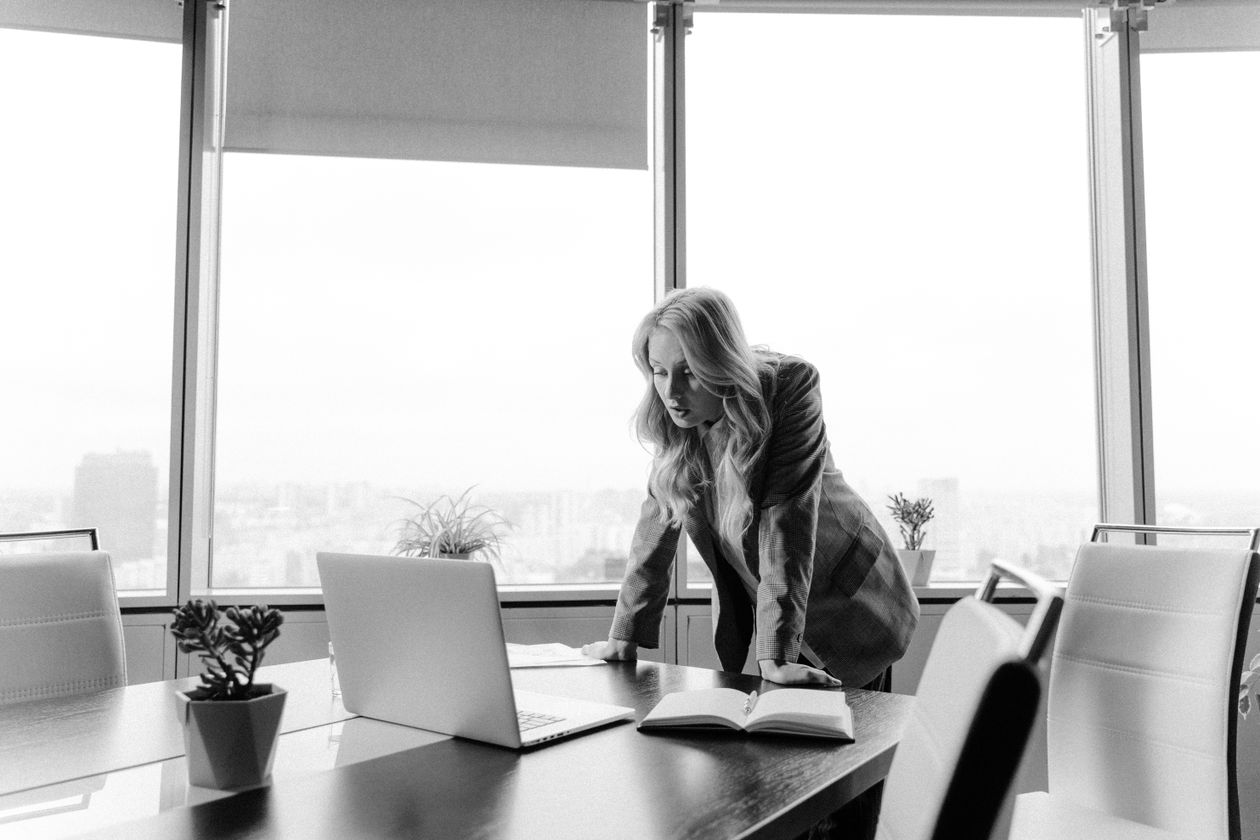 Woman in a blazer in a conference room, running the numbers before committing to an MBA