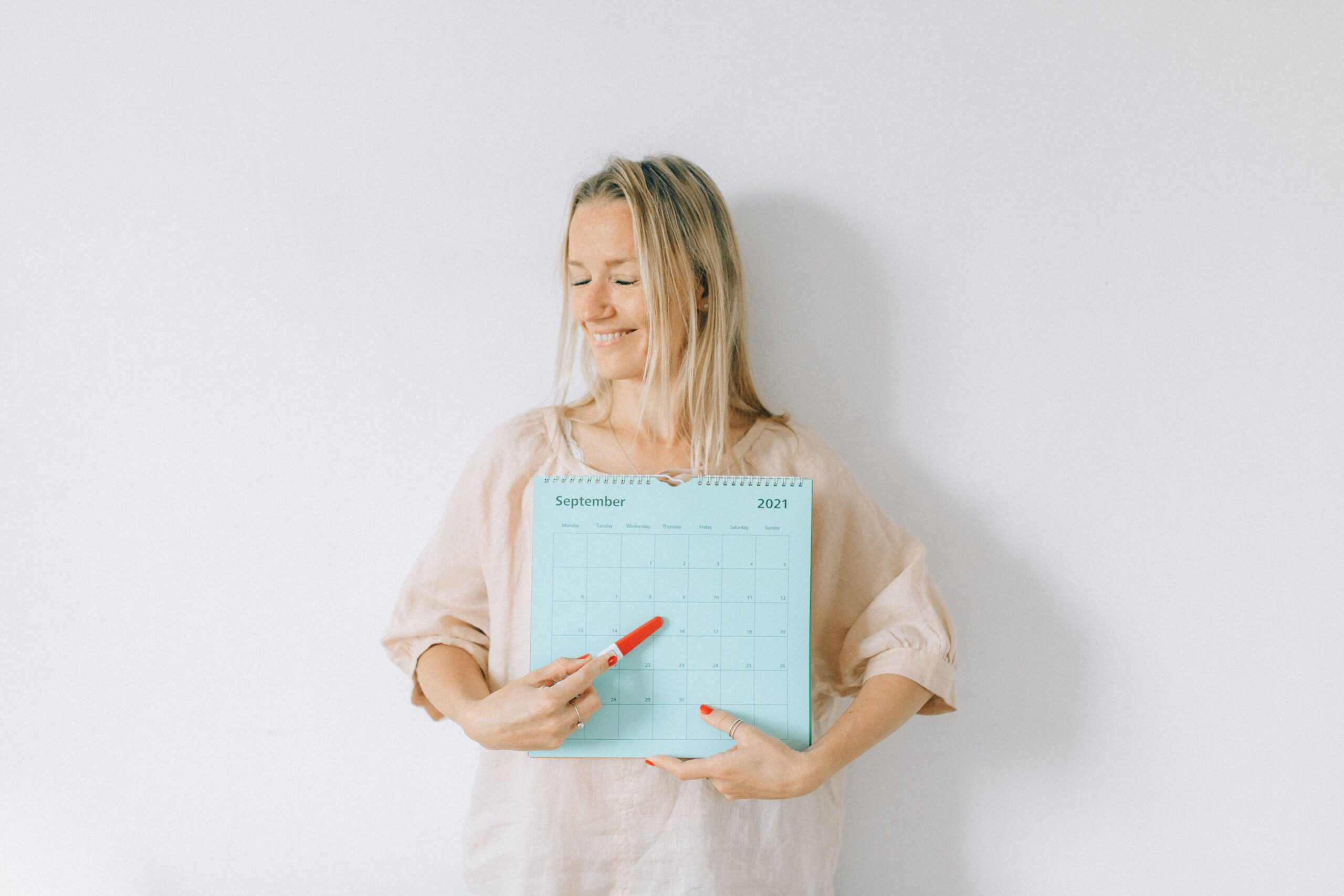 smiling woman pointing at a date on a calendar