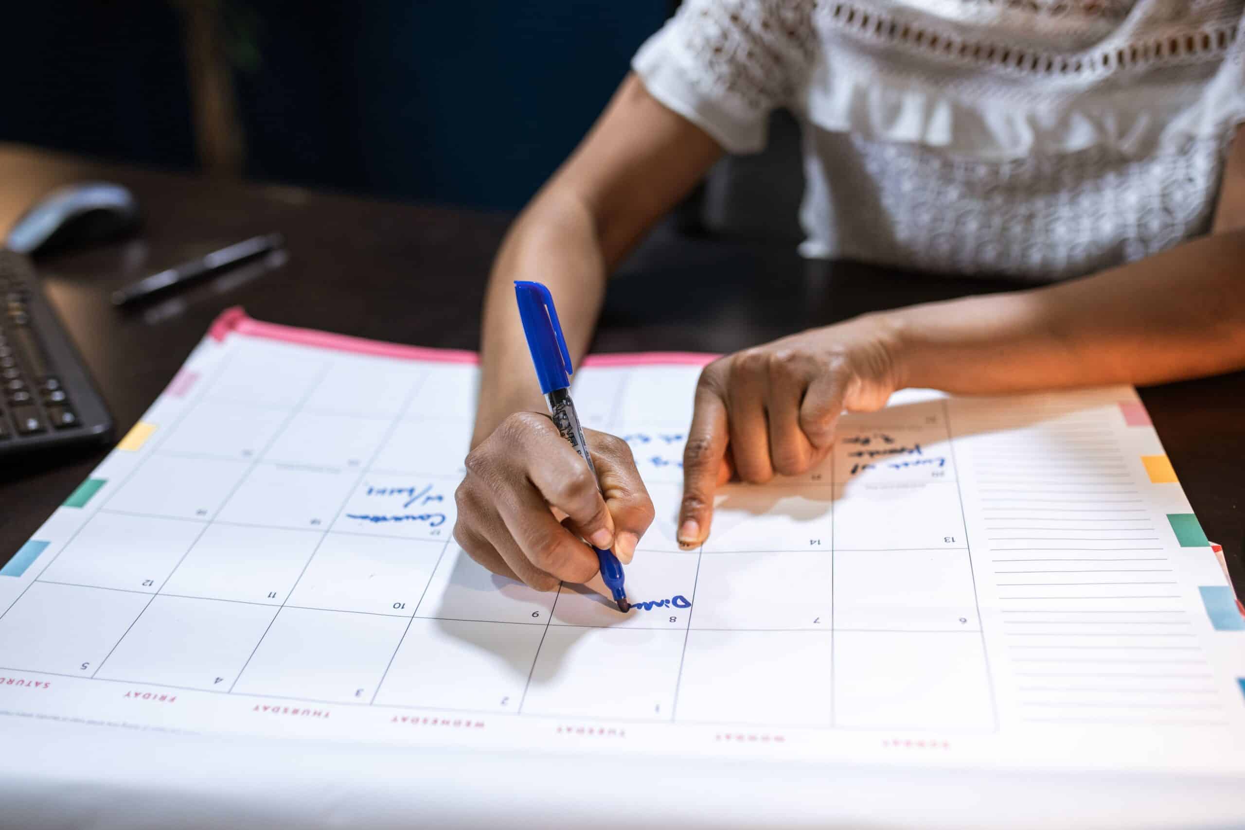 woman marking important dates on a desk calendar