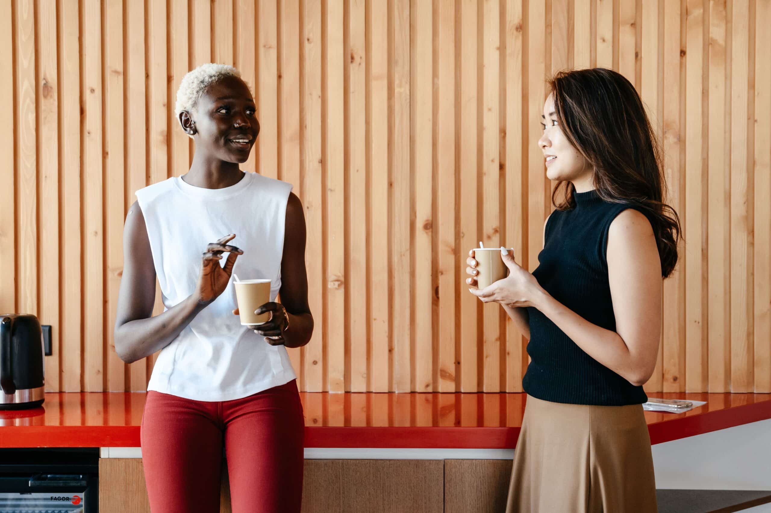 Two women smiling over coffee, discussing building a referral network before a career change at 50