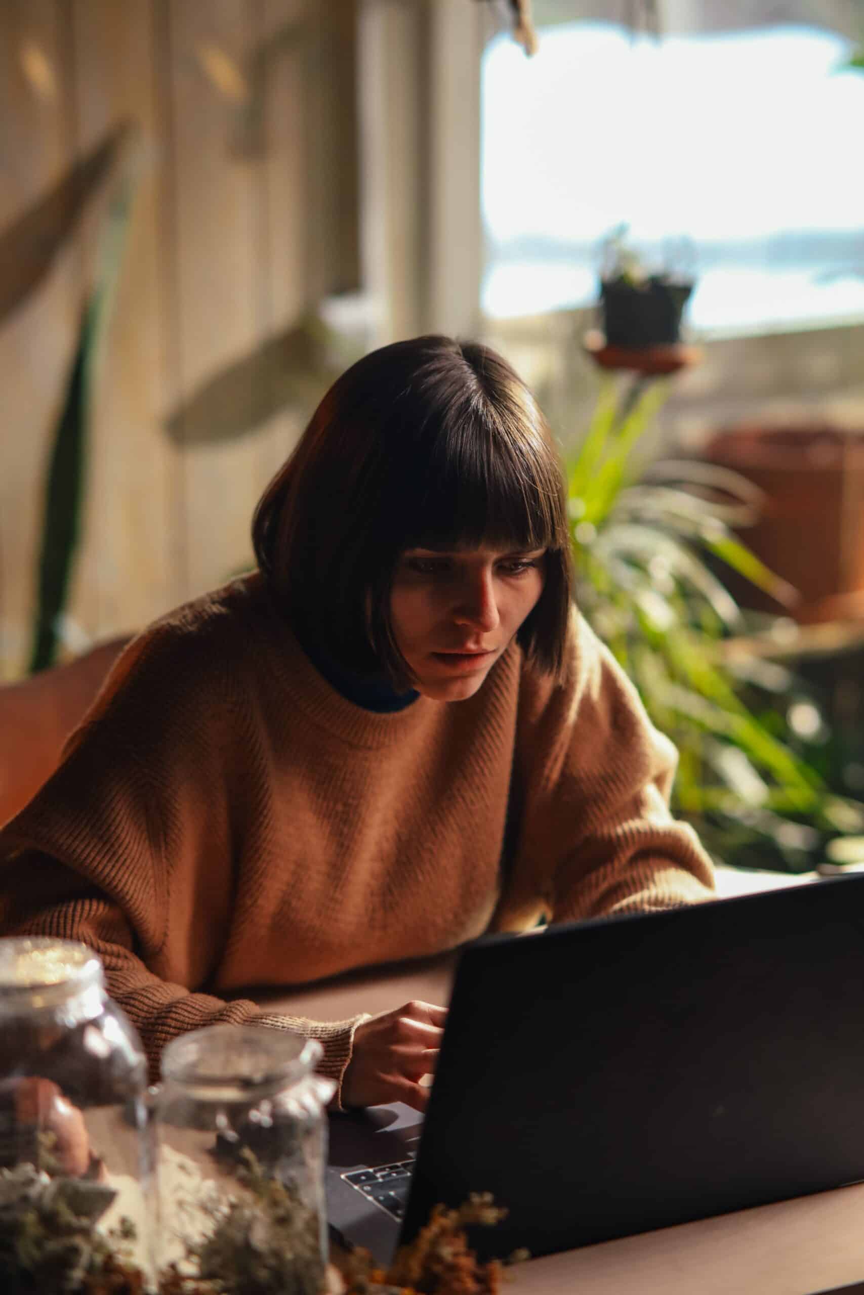 Woman calmly working on a laptop in a sunlit room, choosing among no-degree career paths