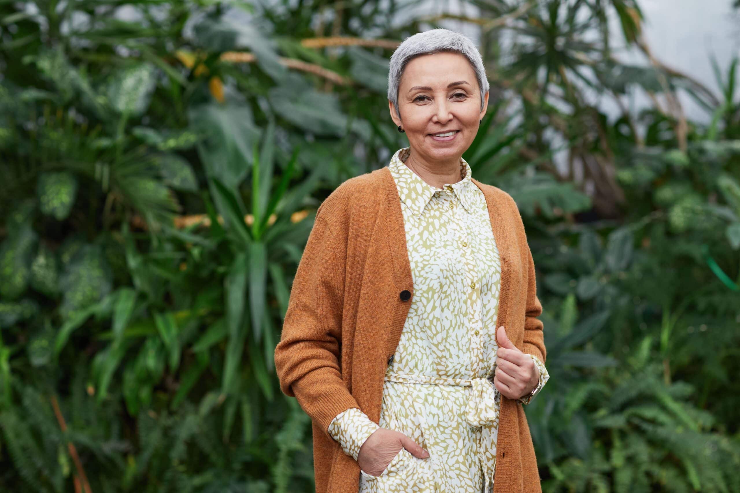 Joyful woman in her 50s smiling in a bright greenhouse, representing personal growth during a step-by-step career change plan