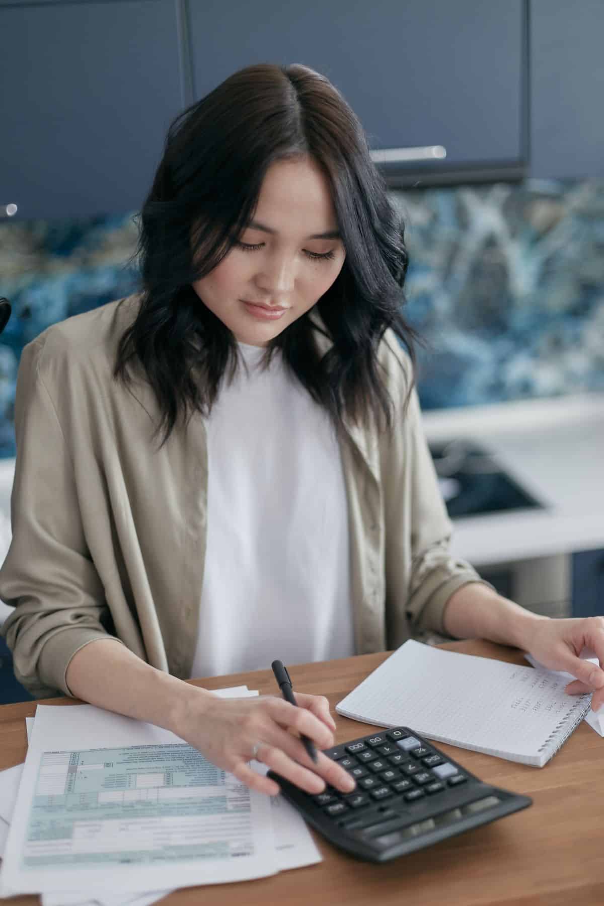 Woman budgeting and reviewing bills, life coach certification real costs