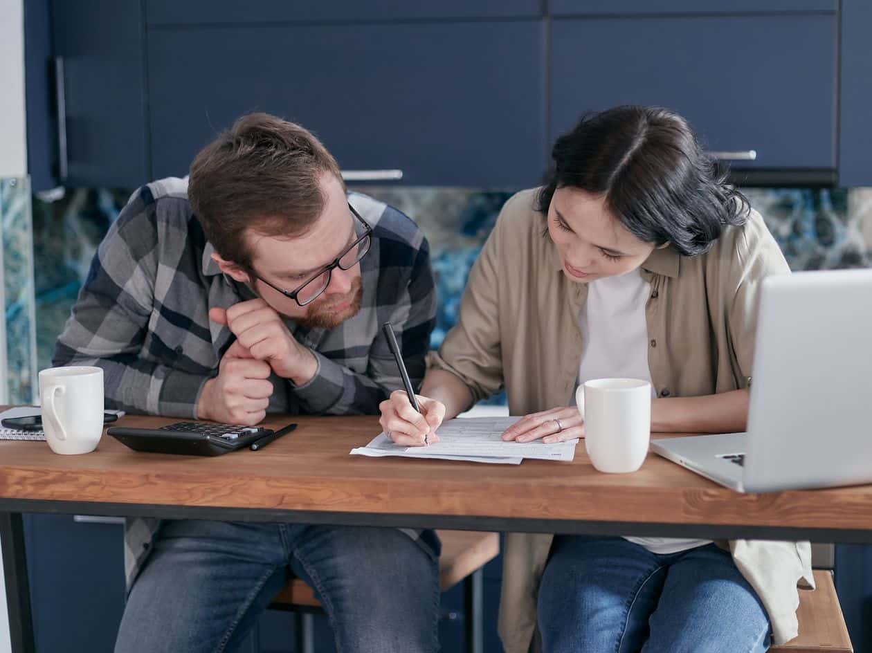 Woman writing on paper beside a man reviewing a financial plan