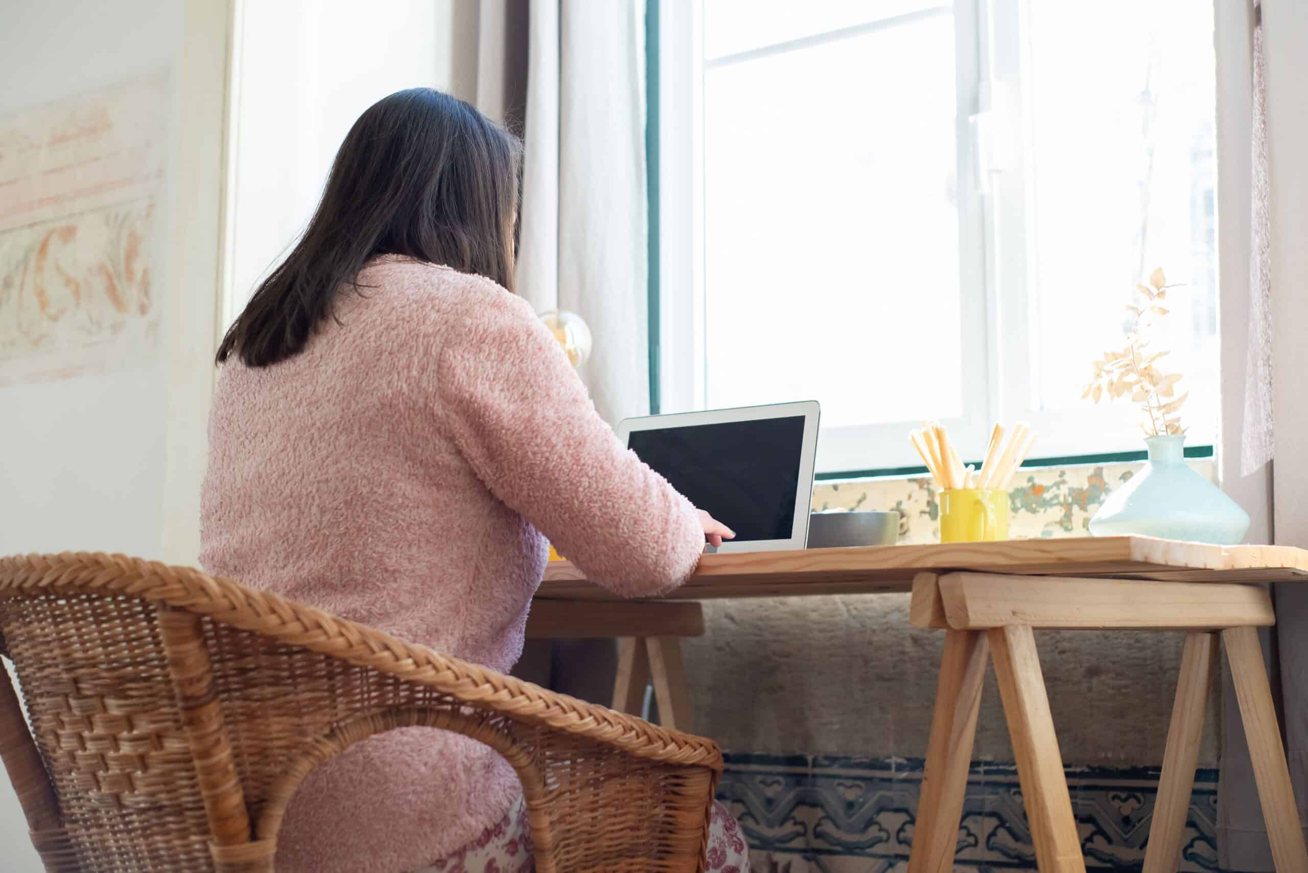 businesswoman working at a wooden desk near a window at home