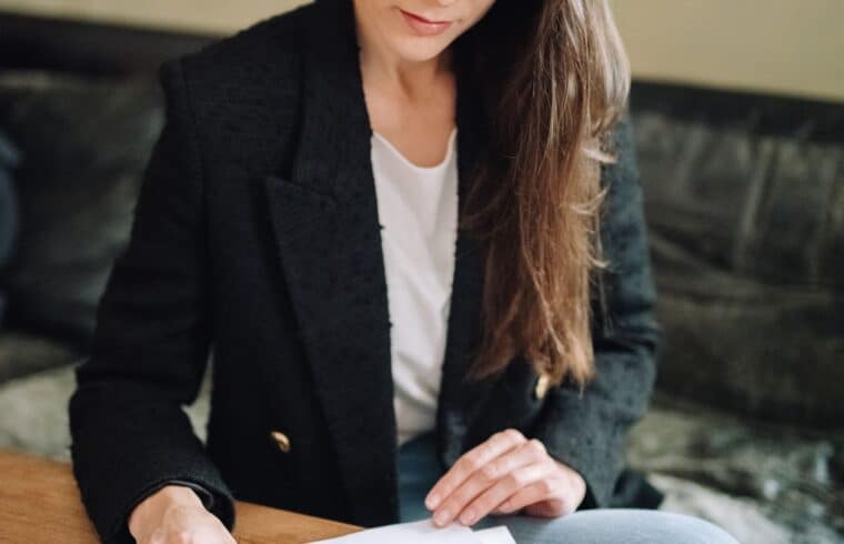 Woman in a blazer reviewing documents at her desk while researching small business grants