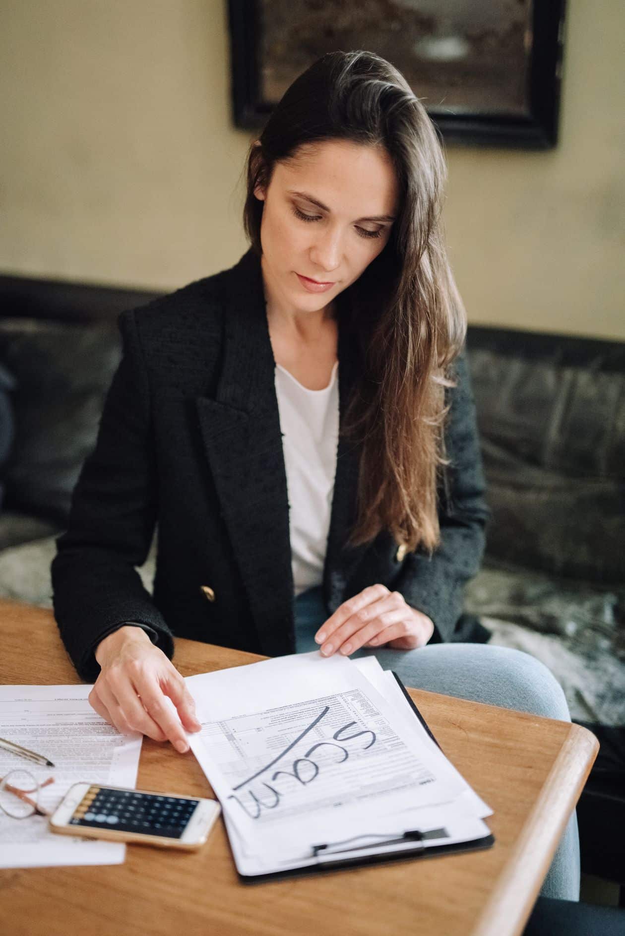 Woman in a blazer reviewing documents at her desk while researching small business grants