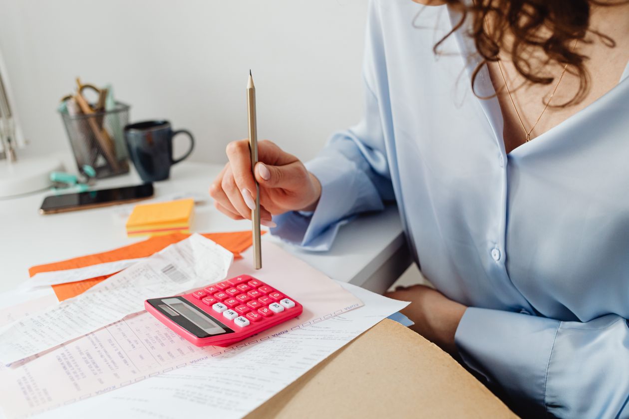 Woman computing bills while holding a pencil, weighing aid sources for adult and career-change students