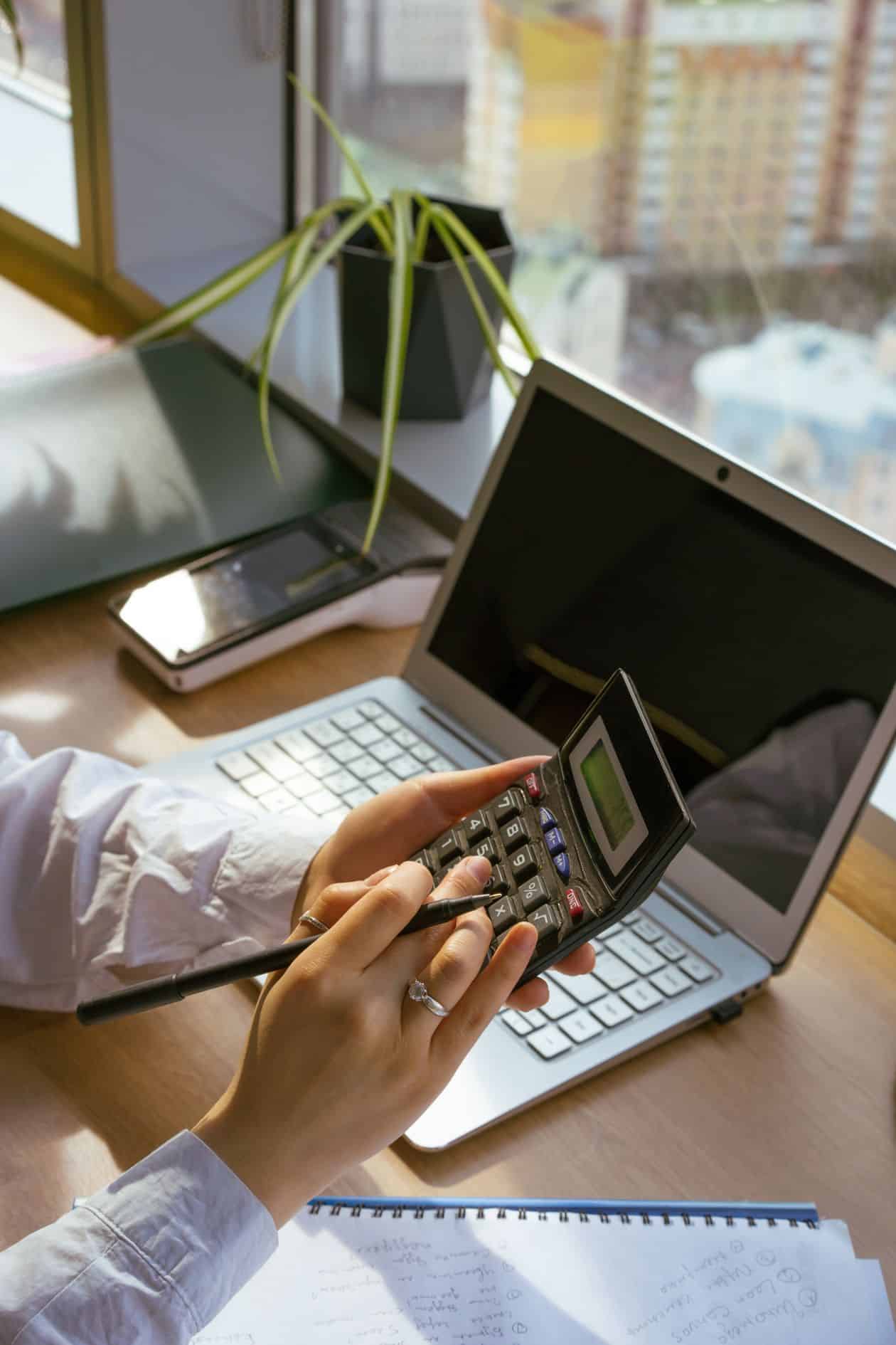 Person using a calculator and a laptop to price out training costs