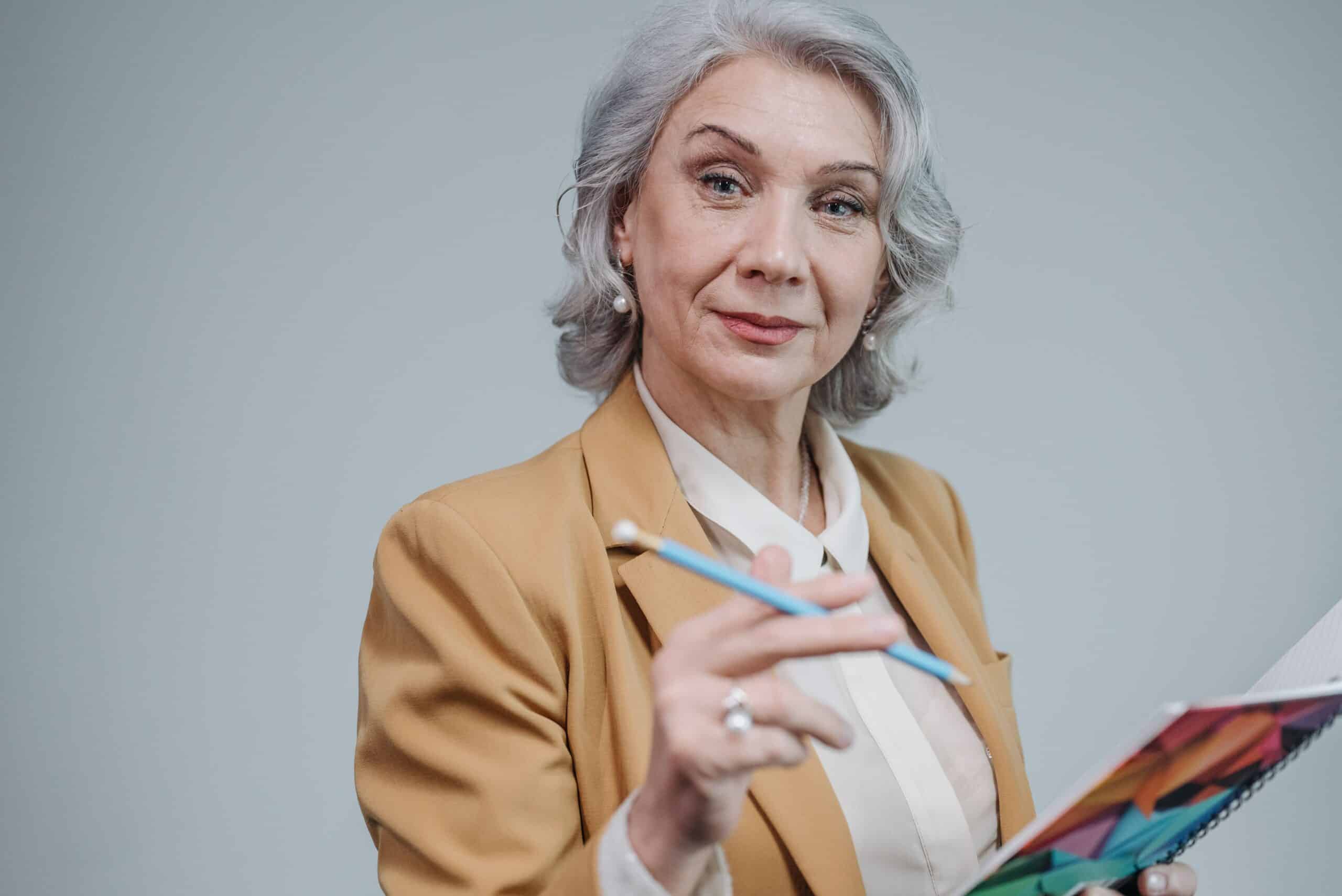 senior woman in a blazer smiling while holding a notebook