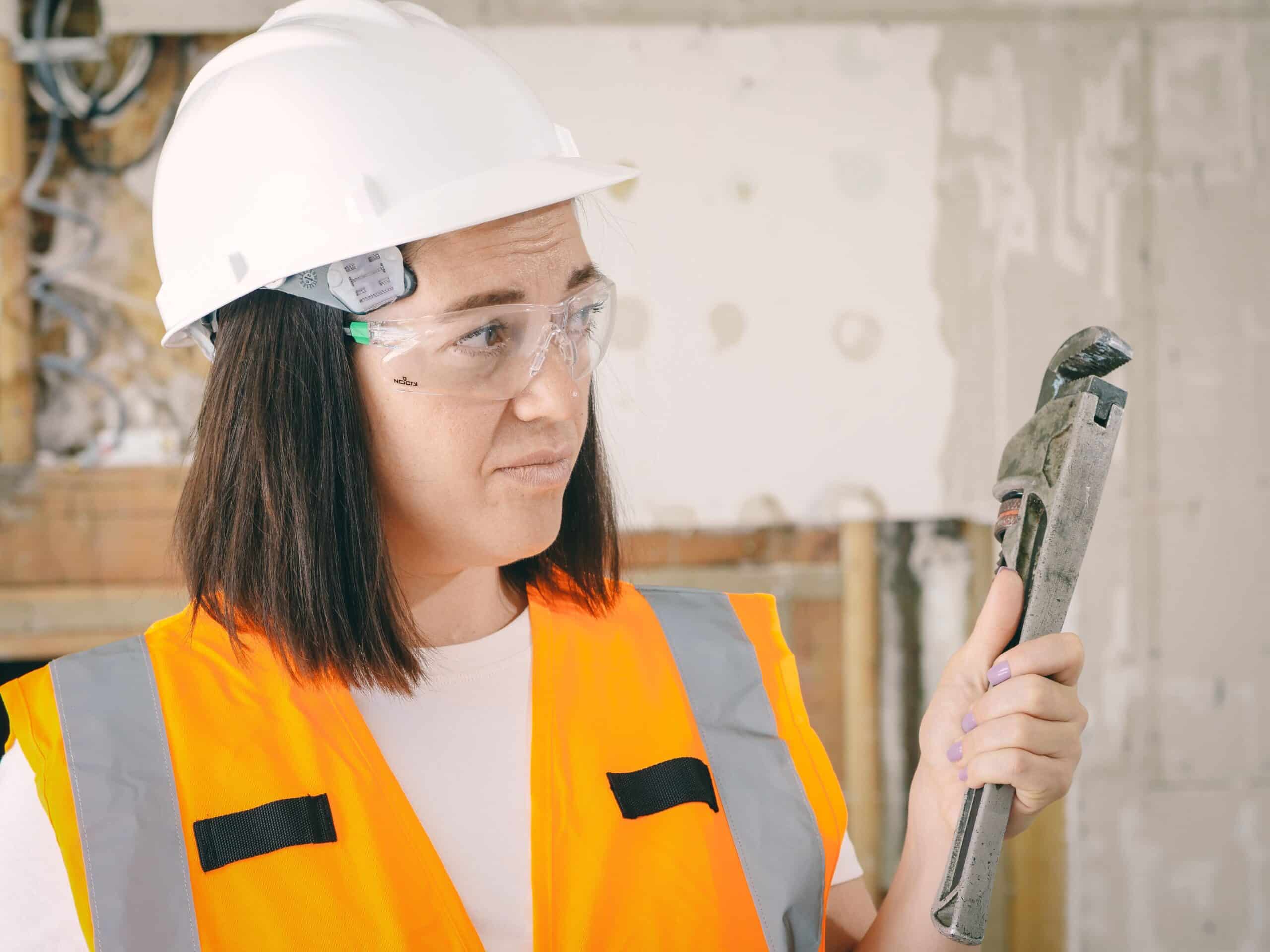 Woman in protective gear holding a wrench, representing a licensing or apprenticeship path career