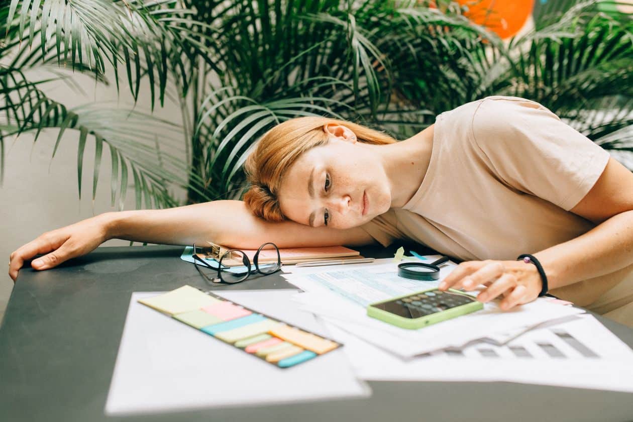 Woman using a calculator and smartphone, working through a financial aid order of operations