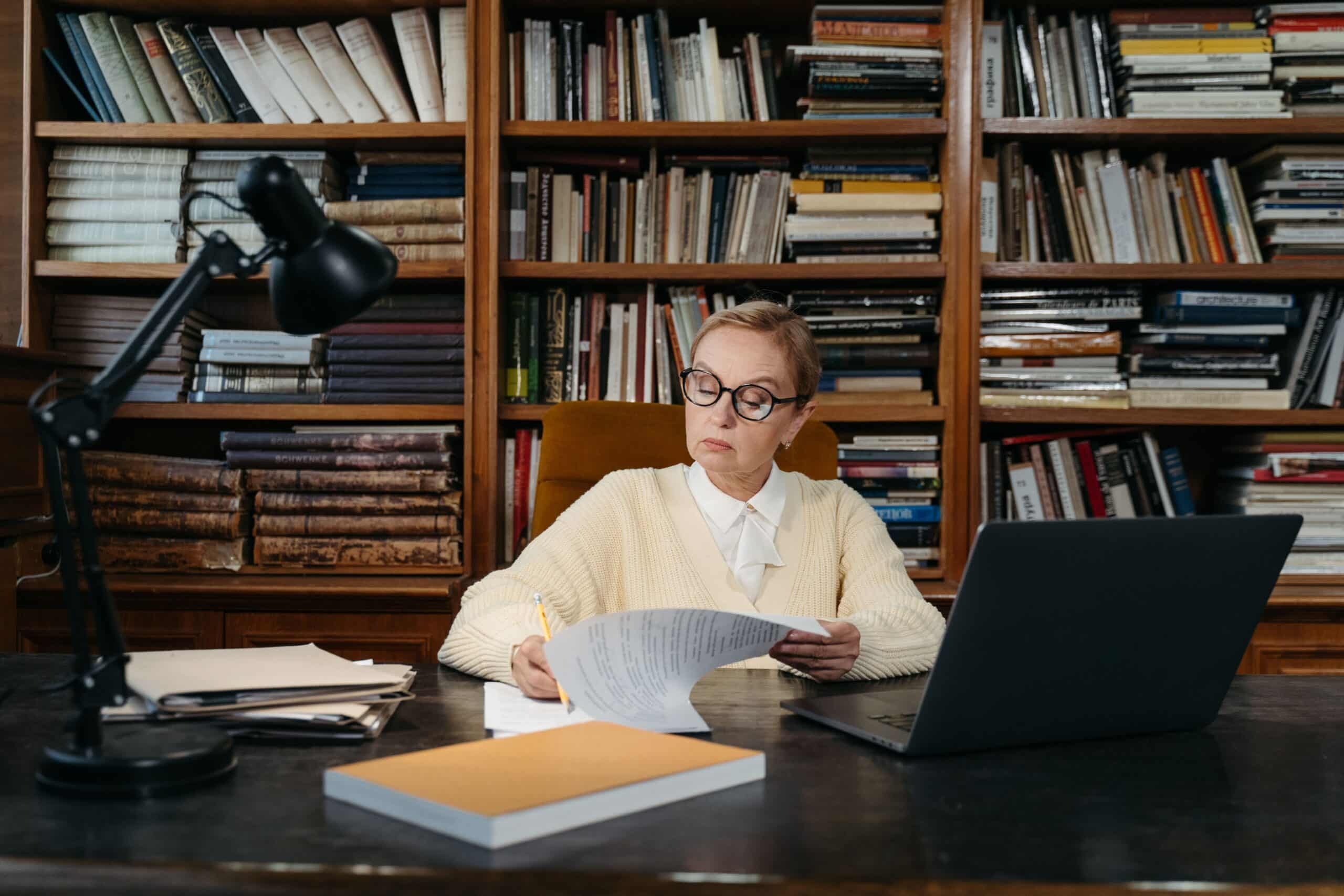 Senior woman reading documents at a desk, reviewing what stays the same in a career change at 50